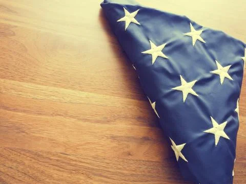 Folded American flag into a triangular shape on an old walnut office table with Stock Photos