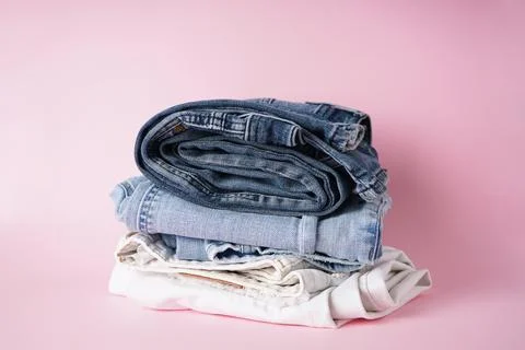 Folded assorted jeans on a pink background. Stock Photos