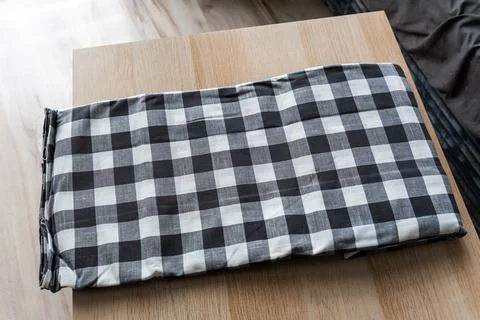 Folded black and white checked tablecloth on wooden table, perfect for home 스톡 사진