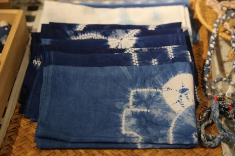 Folded blue and white patterned textiles stacked on a woven tray Foto stock