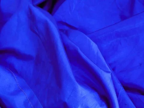 Folded blue fabric cwith soft and flowing lines perfect for texture background Fotos Stock