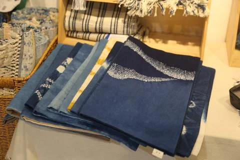 Folded blue textiles with patterned edges on a retail display table 스톡 사진