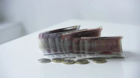 Folded Bristish Ten Pound Notes And One Pound Coins Left On The Table With Stock Footage 142241599