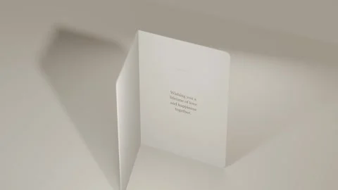 Folded card rotating and opening on beige surface, revealing gold foil front and 動画素材 339721856