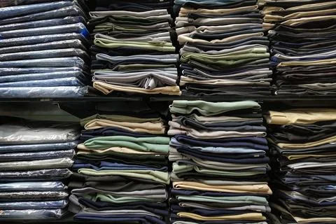 Folded clothes in rack in cloth store Stock Photos