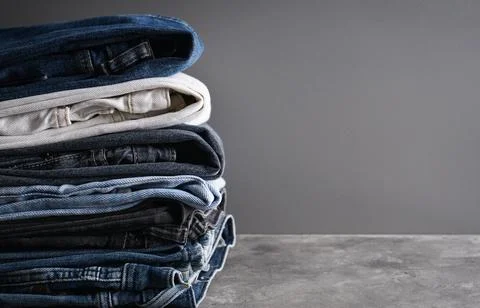 Folded jeans on gray background with space for text. Stock Photos