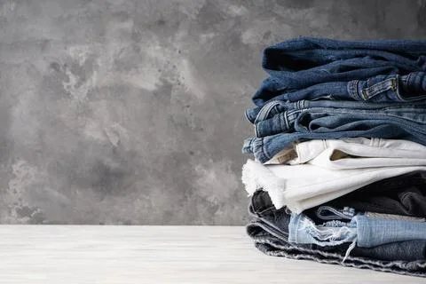 Folded jeans on gray background with space for text. Stock Photos