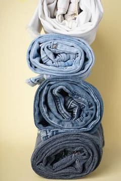 Folded jeans on a yellow background. Vertical Stock Photos