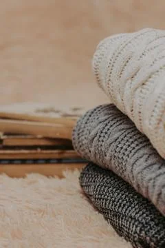 Folded knitted woolen sweaters, stack of old books on a cozy fluffy beige bla Foto stock