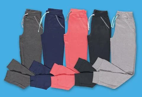 Folded multi-colored jogging pants. Set. Blue background. Stock Photos