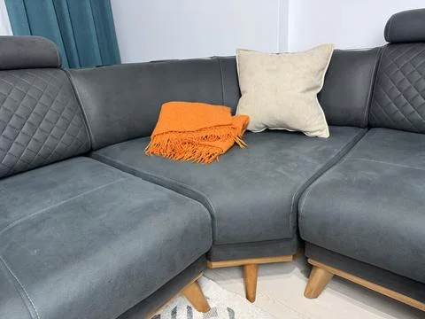 Folded orange blanket on gray sofa in living room Stock Photos