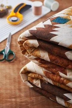 Folded patchwork blanket on wooden surface on sewing accessories background Stock-Fotos