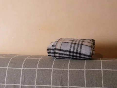 Folded plaid blanket on the back of a sofa, simple cozy interior with neutral Stock Photos