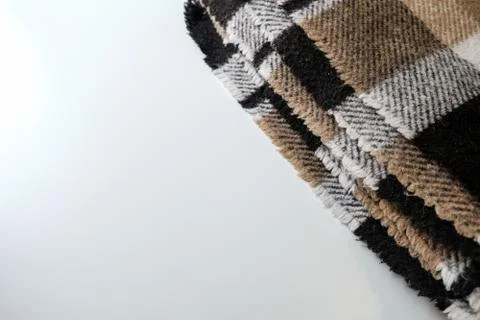 Folded plaid blanket with geometric pattern on a white table. Space for copy Stock Photos