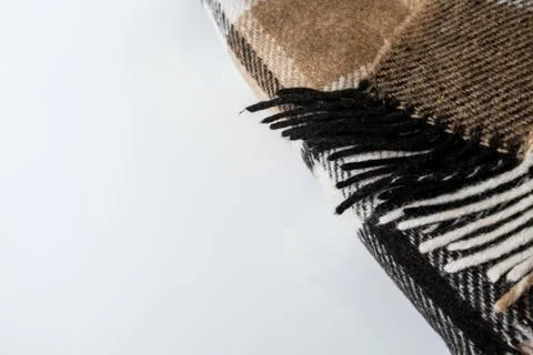 Folded plaid blanket with geometric pattern with ends on a white desk. Stock Photos