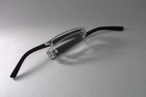 Folded reading glasses, broken in half along the bridge between the lenses Stock Photos