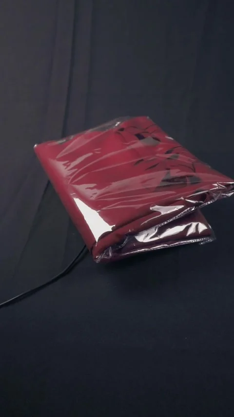 Folded Red Garment In Plastic Package On Dark Background Video stock 322606652