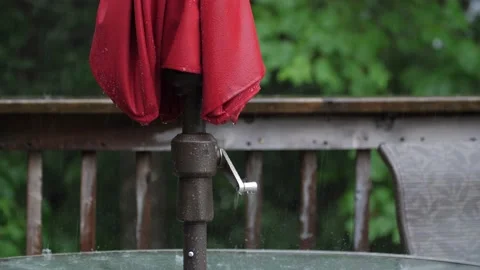 Folded red umbrella on patio deck in pouring rain. Half-speed 4K clip. Vidéo 170664932