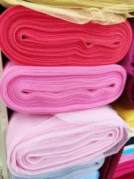 Folded rolls of multi-colored lightweight fabric with expressive texture Stock Photos