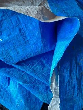 A folded sheet of woven blue plastic tarpaulin showing texture and fabric c.. Stock Photos