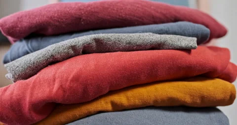Folded stack of clean clothes. Woman's hand presses cotton things. Close-up Stock Footage 235344866