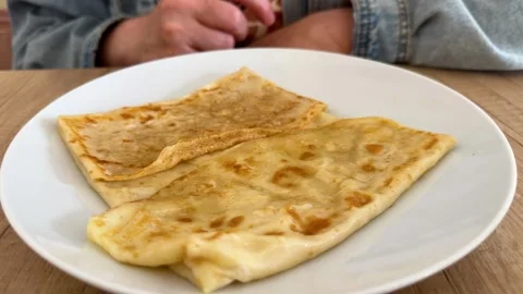 Folded thin pancakes on white plate on wooden table Video stock 342438276
