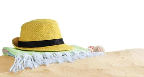Folded towel, hat and shells on sand against white background. Beach objects Stock Photos