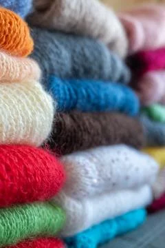 Folded wool sweaters stacked high, soft fuzzy knit texture. Stock Photos