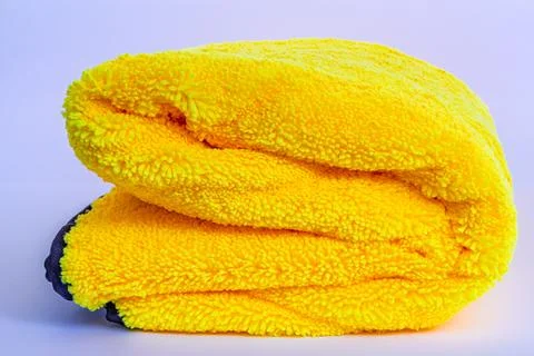 Folded yellow microfiber drying towel with fluffy pile and black edges Stock Photos