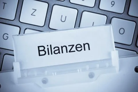 The folder of a hanging file in front of a computer keyboard on the subject of Stock Illustration