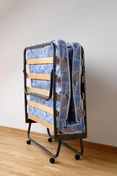 A folding bed in front of a white wall Stock Photos