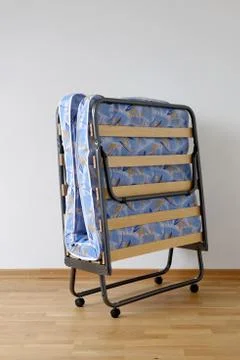 A folding bed in front of a white wall Stock Photos