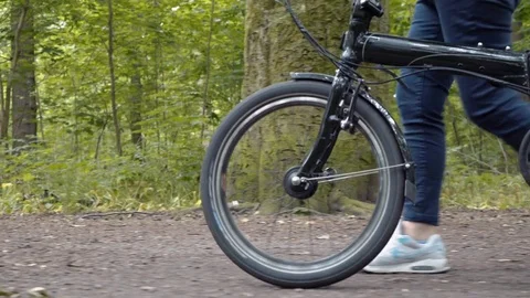 Folding bicycle being pushed in a park by a blonde woman Stock-Footage 78055990
