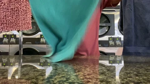 Folding clothes at the laundry mat Stock Footage 210061160