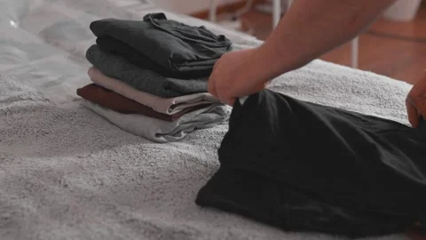 Folding clothes to put into vacuum bag for storage. Wardrobe storage concept. Stock-Footage 305313224