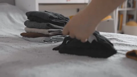 Folding clothes to put into vacuum bag for storage. Wardrobe storage concept. Stock Footage 305313229