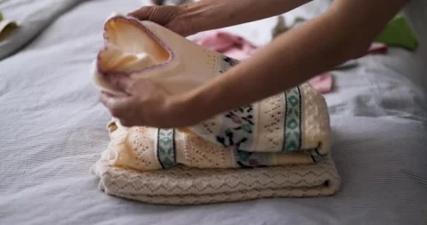 Folding clothing on a bed. Cozy Bed with Folded Clothes. Stock Footage 277970261