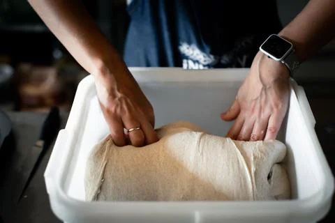 Folding the dough in a container in a bakery Stock Photos