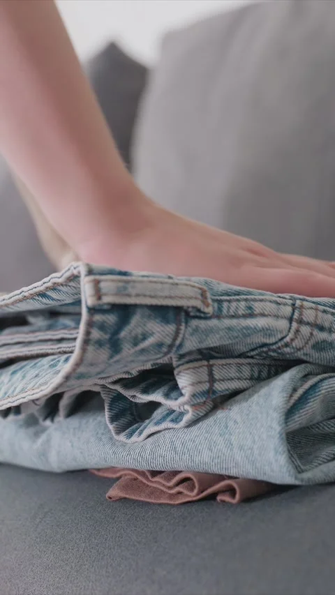 Folding Jeans On Stack Of Folded Clothes In Soft Indoor Lighting featuring Stock Footage 346786461