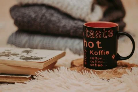Folding knitted woolen sweaters, a stack of old books, a beautiful black and  Stock Photos