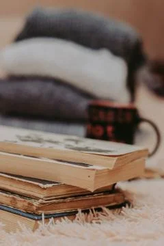 Folding knitted woolen sweaters, a stack of old books, a beautiful black and  Stock Photos