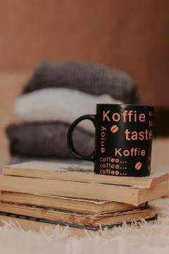 Folding knitted woolen sweaters, a stack of old books, a beautiful black and  Stock Photos