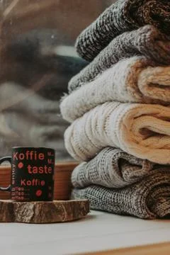 Folding knitted woolen sweaters, a stack of old books, a beautiful black and  Foto stock