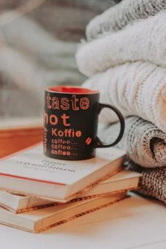 Folding knitted woolen sweaters, a stack of old books, a beautiful black and  Foto stock