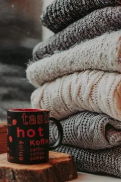 Folding knitted woolen sweaters, a stack of old books, a beautiful black and  Stock Photos