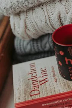 Folding knitted woolen sweaters, a stack of old books, a beautiful black and  Stock Photos