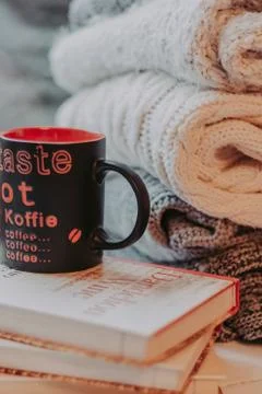 Folding knitted woolen sweaters, a stack of old books, a beautiful black and  Stock Photos
