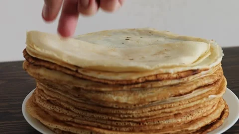 Folding thin crepe from tall stack into triangle shape over white plate on dark Stock Footage 309301967