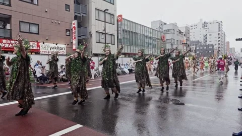 Foliage Costumed Samba Performers Marching Down a Rain Soaked Street Stock Footage 346253643
