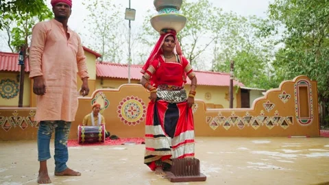 Folk dancer balances pot atop head stands on nails outdoor Stock Footage 304848292
